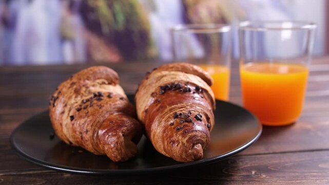 Primo piano di cornetti su piatto nero e due bicchieri di succo d'arancia