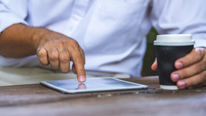 A businessman using a tablet while holding a coffee cup
