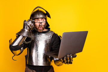 Surprised Male in Medieval Armor Using Modern Laptop Against Yellow Background