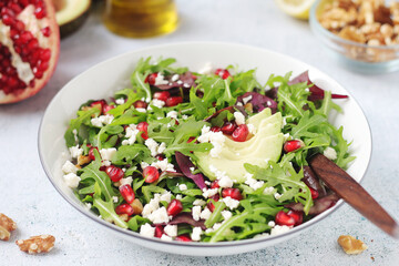A plate with green rocket salad with pomegranate and avocado	