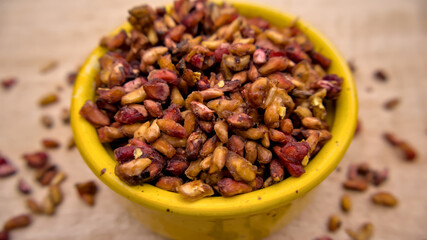Dried Pomegranate Seeds Isolated Closeup in a Yellow Bowl on Wooden Background