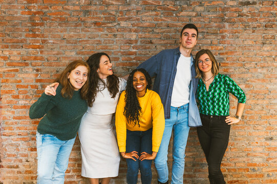 Smiling diverse young adults posing playfully together, symbolizing friendship, teamwork, and togetherness in a fun and inclusive environment.