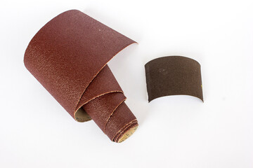 Rolled sandpaper on abrasive background, close-up