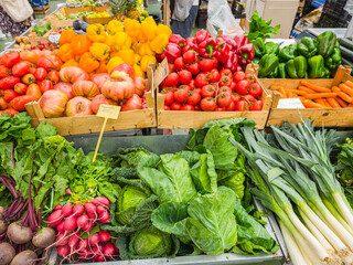 Assortment of fresh organic vegetables and greens on farmers market stall close up.