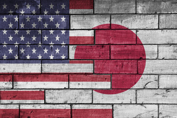 colourful painted big flag of united states of america and flag of japan on a massive old brick wall background. concept