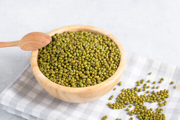 Plant-based mung beans for wholesome dishes in wooden bowl and scoop e on light gray table background. Healthy plant-based protein, healthy cooking ingredient for vegan recipes and vegetarian diets