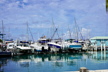 Fototapeta premium The water of Great Bay at Bobby's Marina in Philipsburg, St. Maarten is so calm on this day that clear reflections appear of the boats parked there, complete with masts.