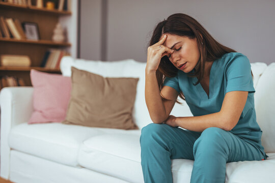 Exhausted Healthcare Worker Sitting on Couch in Stressful Moment