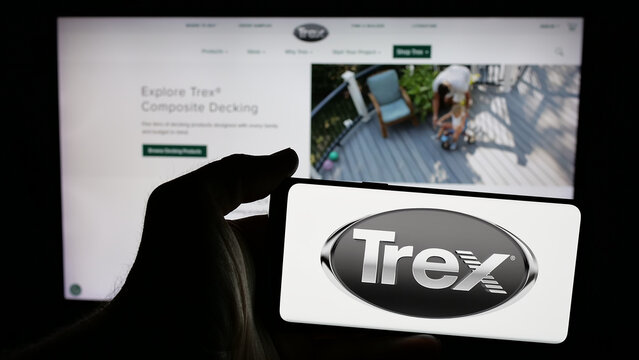 Stuttgart, Germany - 01-15-2025: Person holding mobile phone with logo of American decking business Trex Company Inc. on screen in front of web page. Focus on phone display.