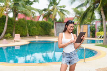 Woman using digital tablet around swimming pool