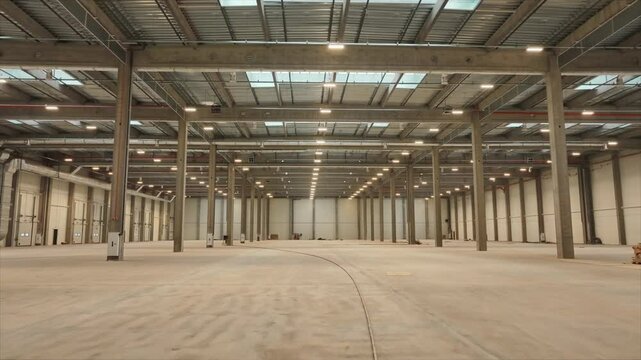 Horizontal shooting of big modern lighted industrial space. Logistics warehouse inside. Footage of storage for goods. Interior of empty hub. High roofs. Distribution center. No one. Indoors