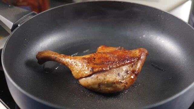 Golden brown duck confit searing in cast iron skillet, releasing crispy skin layer and intensifying classic french culinary flavors with caramelizing edges. High cuisine. Chef cooking in restaurant