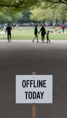 People strolling along scenic park paths, enjoying nature, with a sign in the foreground reading Offline Today, symbolizing mindful relaxation and a break from technology.