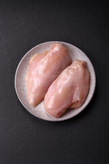 Fototapeta premium Fresh chicken fillet on a dark concrete table with spices and herbs