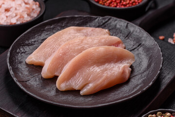 Fresh chicken fillet on a dark concrete table with spices and herbs