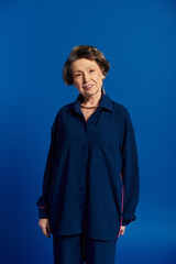 Stylish woman in her 60s confidently poses in trendy attire, radiating elegance and beauty.