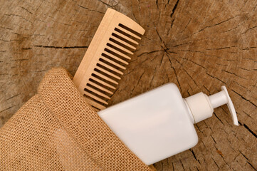 Obraz premium White plastic container with dispenser and wooden comb in a canvas bag.