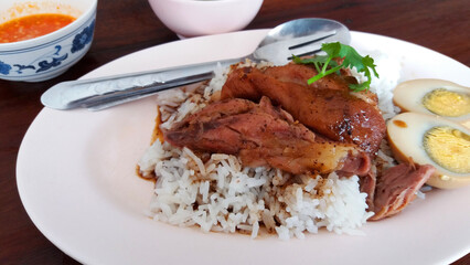 Close up Stewed pork leg with boiled egg on rice. Thai or famous food in Tbailand on wood table.