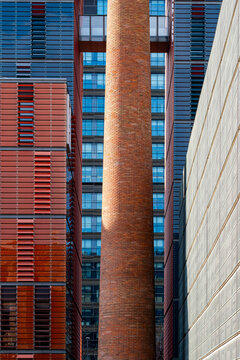 This image features a striking mix of modern glass architecture and a tall red brick chimney, illustrating the blending of new and historical architectural elements.
