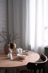 A stylish dining table with a charming vase, elegant dishes, bowl with oatmeal bowl, egg. Easter decoration.