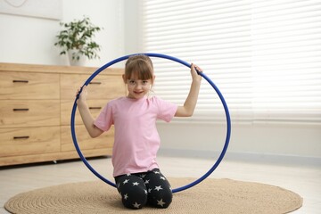 Cute little girl with hula hoop on floor at home