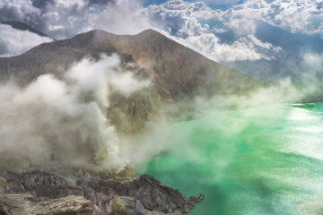 The breathtaking landscape of a volcanic crater acid lake showcases turquoise waters that are beautifully contrasted by majestic mountains that are enveloped in mist East Java, Ijen Volcano, Indonesia
