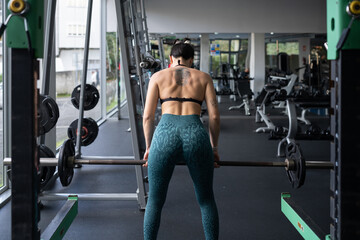 Muscular female weightlifter executing heavy barbell deadlift, demonstrating intense physical...