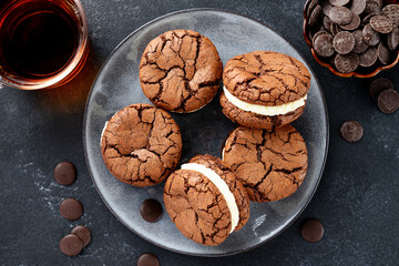 Chocolate sandwich cookies, brownie biscuits with  cream cheese filling, dark background, top view