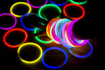 Girl wrist with rainbow bracelets. Neon glow party lights in the dark