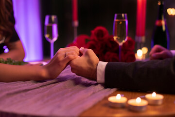 She said yes. Man holding lady's hand with engagement ring, having romantic date in restaurant. Engagement celebration at Valentine's day
