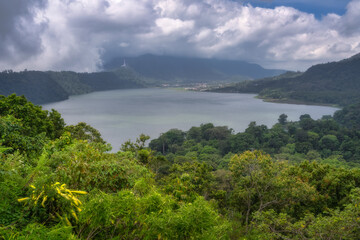 A breathtaking view of a serene and tranquil lake framed beautifully by lush green hills and soft, fluffy clouds reveals natures unparalleled and unmatched beauty, Bali, Indonesia