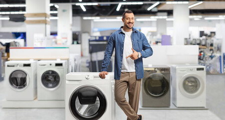 Young man pointing at a washing machine