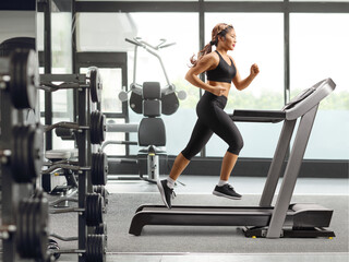Fototapeta premium Young asian female running on a treadmill