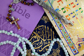 Bible, Quran and Torah. Concept of interfaith dialogue.  Christianity, Islam and Judaism, the three monotheistic religions. Religious symbols : christian cross, yad, prayer beads.