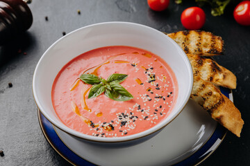 Fresh tomato soup with sesame seeds, basil garnish, and toasted bread for a comforting meal