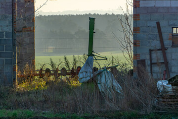 old abandoned brick barn with old agricultural equipment for raking hay in the field overlooking...