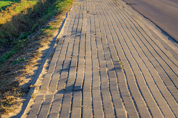 uneven country sidewalk. poorly laid paving stone sidewalk.