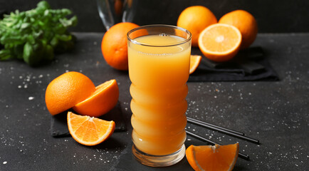 Glass of fresh orange juice and fruit on dark background