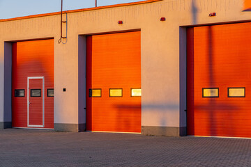 red sectional doors in a fire station with falling sunlight. fire brigade trips.
