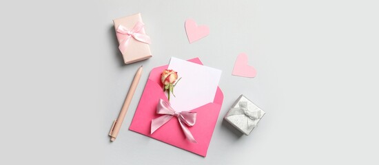 Envelope with blank card, beautiful rose and gift boxes on grey background. Valentine's day...