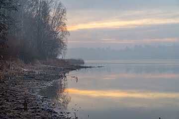 lake landscape in the morning. magical cold frosty morning by the lake. sunrise over a foggy lake. dirty beach