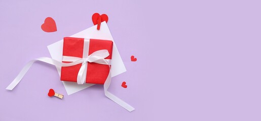 Gift box for Valentine's Day and paper hearts on lilac background with space for text