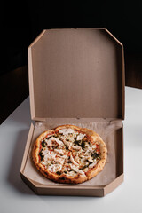 Italian pizza with chicken and sauce in a cardboard box. Pizza delivery