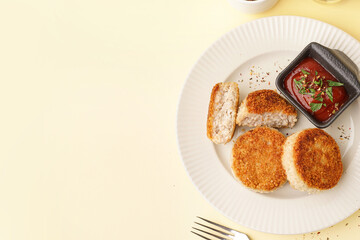 Plate with tasty meat cutlets and sauce on yellow background