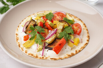 Plate of tasty pita bread with grilled vegetables on white background
