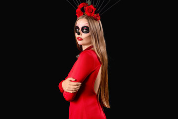 Young woman with painted skull on her face against black background. Celebration of Mexico's Day of the Dead (El Dia de Muertos)