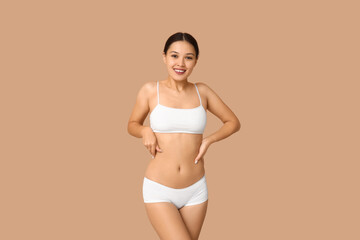 Obraz premium Slim young woman in underwear on beige background. Weight loss concept