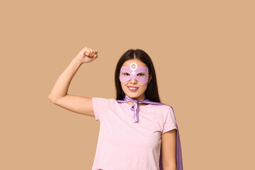 Young woman in superhero costume on beige background. Women's history month