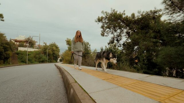 Casual modern blonde woman Husky dog owner walking together smiling relaxing enjoy friendship