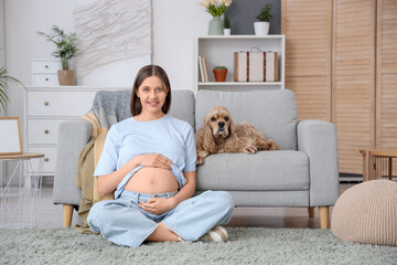 Beautiful pregnant woman with cocker spaniel on sofa at home
